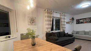 Un coin repas avec une table et des chaises en bois, une plante en pot et un luminaire moderne.