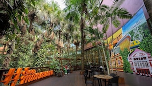 Ein Restaurant mit Holzboden, Tischen, Stühlen und Wandgemälde.