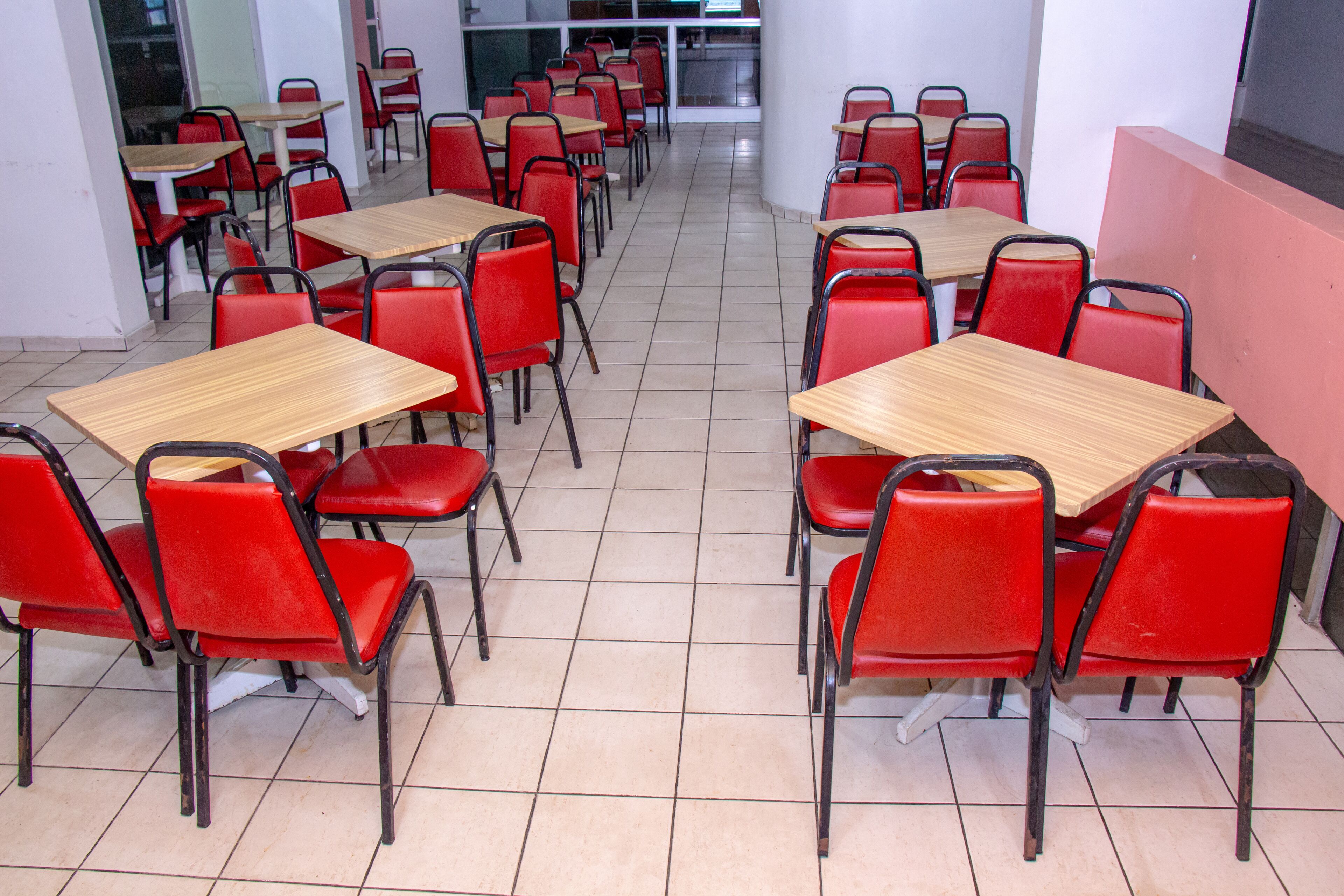 Una cafetería con sillas rojas y mesas de madera dispuestas en filas.