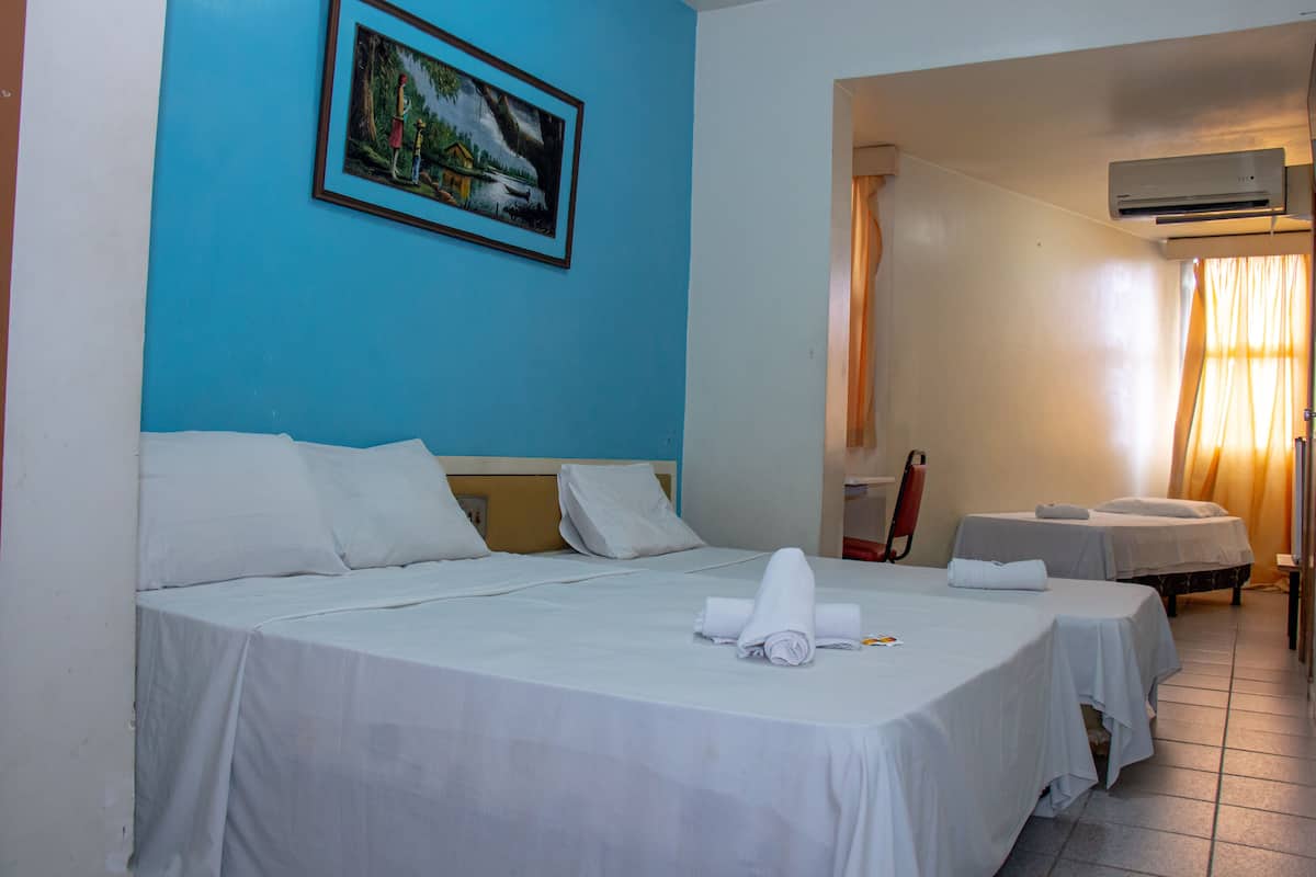 Ein Hotelzimmer mit zwei Betten, einem Bild an der Wand und einer Klimaanlage.