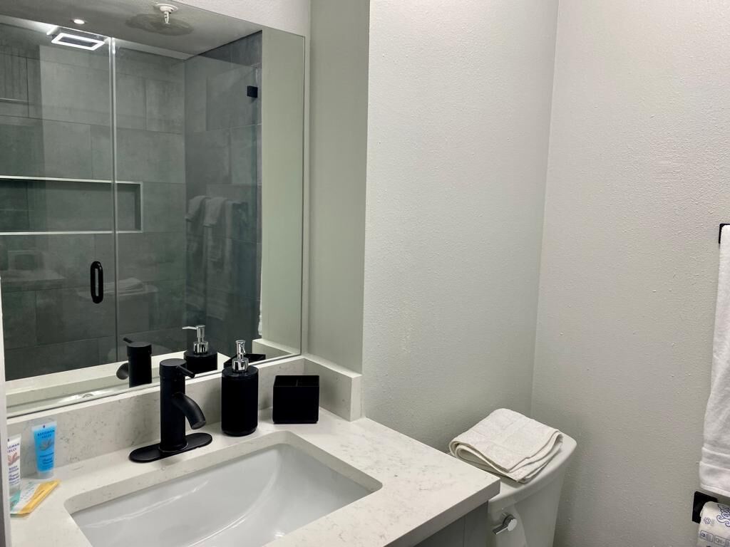 Un baño moderno con un espejo grande, un lavamanos y un inodoro.