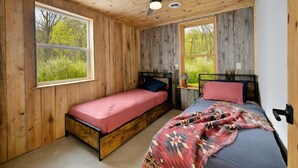 A cabin bedroom with two beds, wooden walls, and large windows. - Renovated Rustic Lodge/Historic property.
Hike, fish, star gaze. w/artist studio (Port Washington)