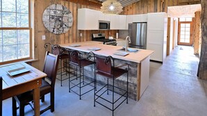 A kitchen with a central island, wooden cabinets, and a large window. - Renovated Rustic Lodge/Historic property.
Hike, fish, star gaze. w/artist studio (Port Washington)