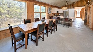 A rustic cabin interior with a dining area, kitchen, and large windows overlooking a forest. - Renovated Rustic Lodge/Historic property.
Hike, fish, star gaze. w/artist studio (Port Washington)