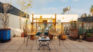 An outdoor patio with two wicker chairs, a table, and potted plants. - Riad Alena Marrakech (Marrakech)