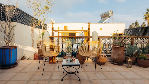 An outdoor patio with two wicker chairs, a table, and potted plants. - Riad Alena Marrakech (Marrakech)