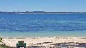 A beach with clear water and distant mountains. - Casa Carinho, 24 Wallawa Rd - spectacular water views, pet friendly, air con and Wi-Fi (Nelson Bay)