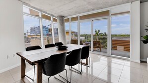 A modern dining area with a large table and chairs, large windows with a view of buildings and a balcony. - Amazing sunset view with Pool, 2b/2ba, gym , Best location A+! (Miami)