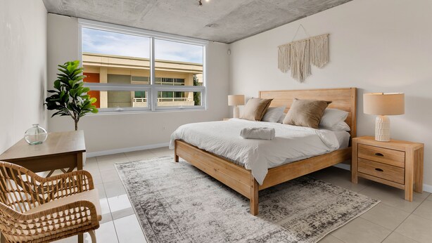A modern bedroom with a large bed, bedside tables, a desk, and a chair. - Amazing sunset view with Pool, 2b/2ba, gym , Best location A+! (Miami)