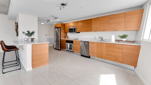 A modern kitchen with wooden cabinets, stainless steel appliances, and a white countertop. - Amazing sunset view with Pool, 2b/2ba, gym , Best location A+! (Miami)