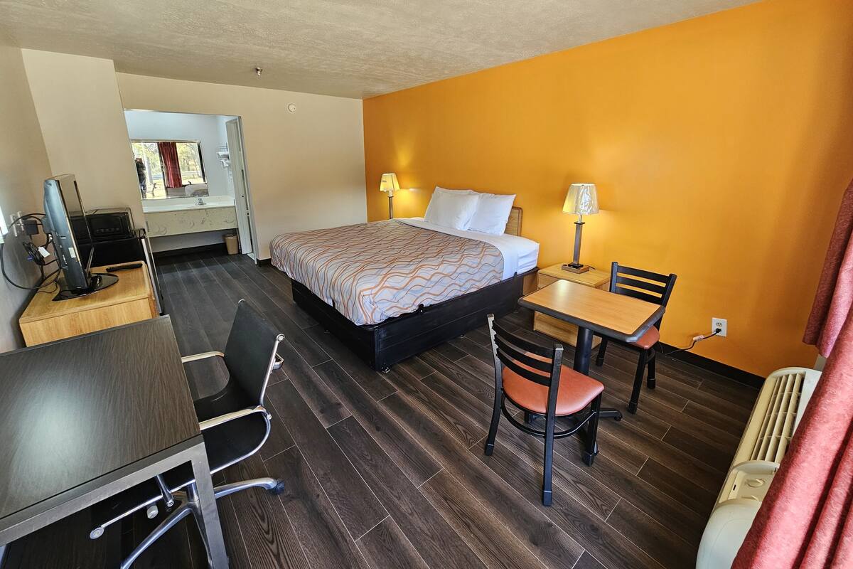 A hotel room with a bed, desk, chair, and a small table.