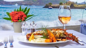 Un plat de fruits de mer accompagné d’un verre de vin blanc, servis sur une table au bord de la mer.