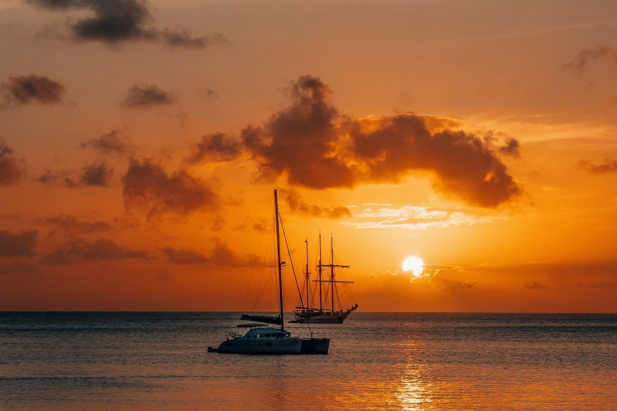 Un atardecer sobre el océano con veleros.