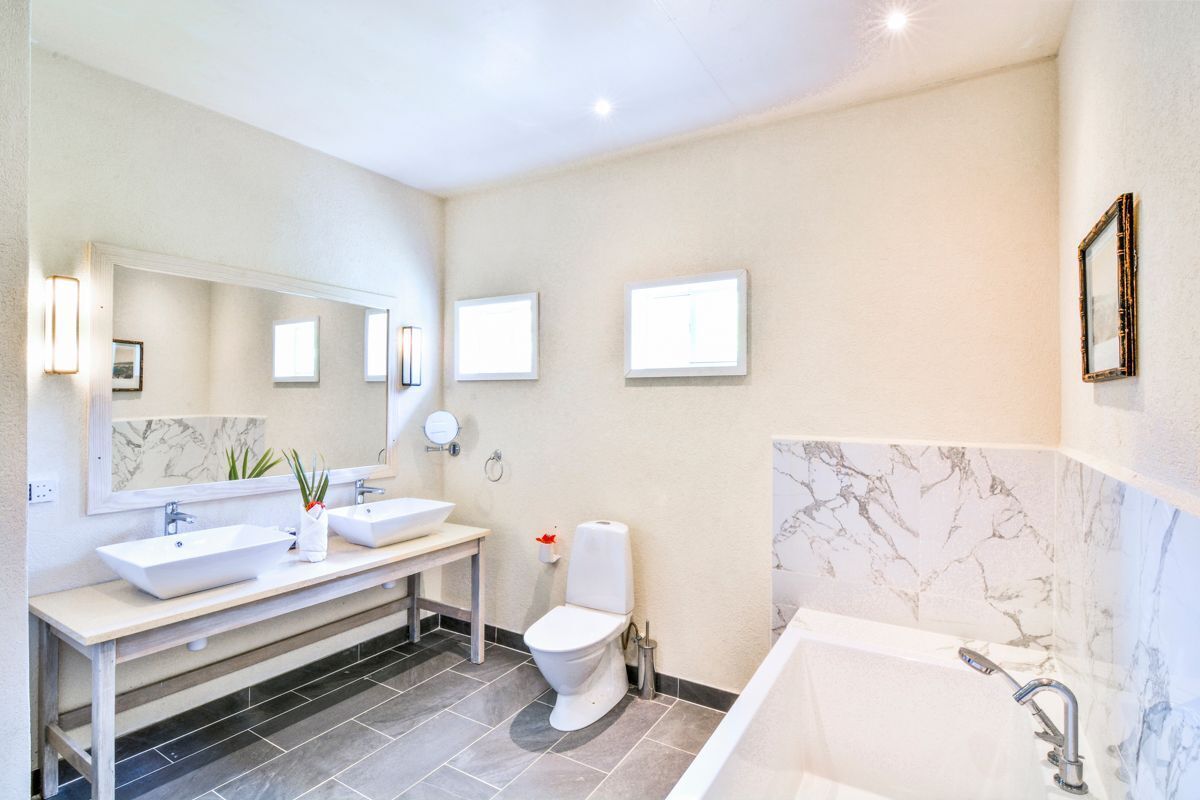 A modern bathroom with a double sink vanity, a toilet, and a bathtub.