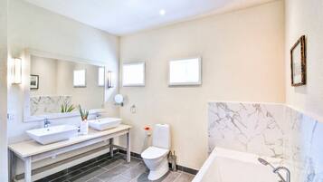 A modern bathroom with a double sink vanity, a toilet, and a bathtub.