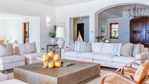 Un salon moderne avec un grand canapé, une table basse et des fauteuils en osier.