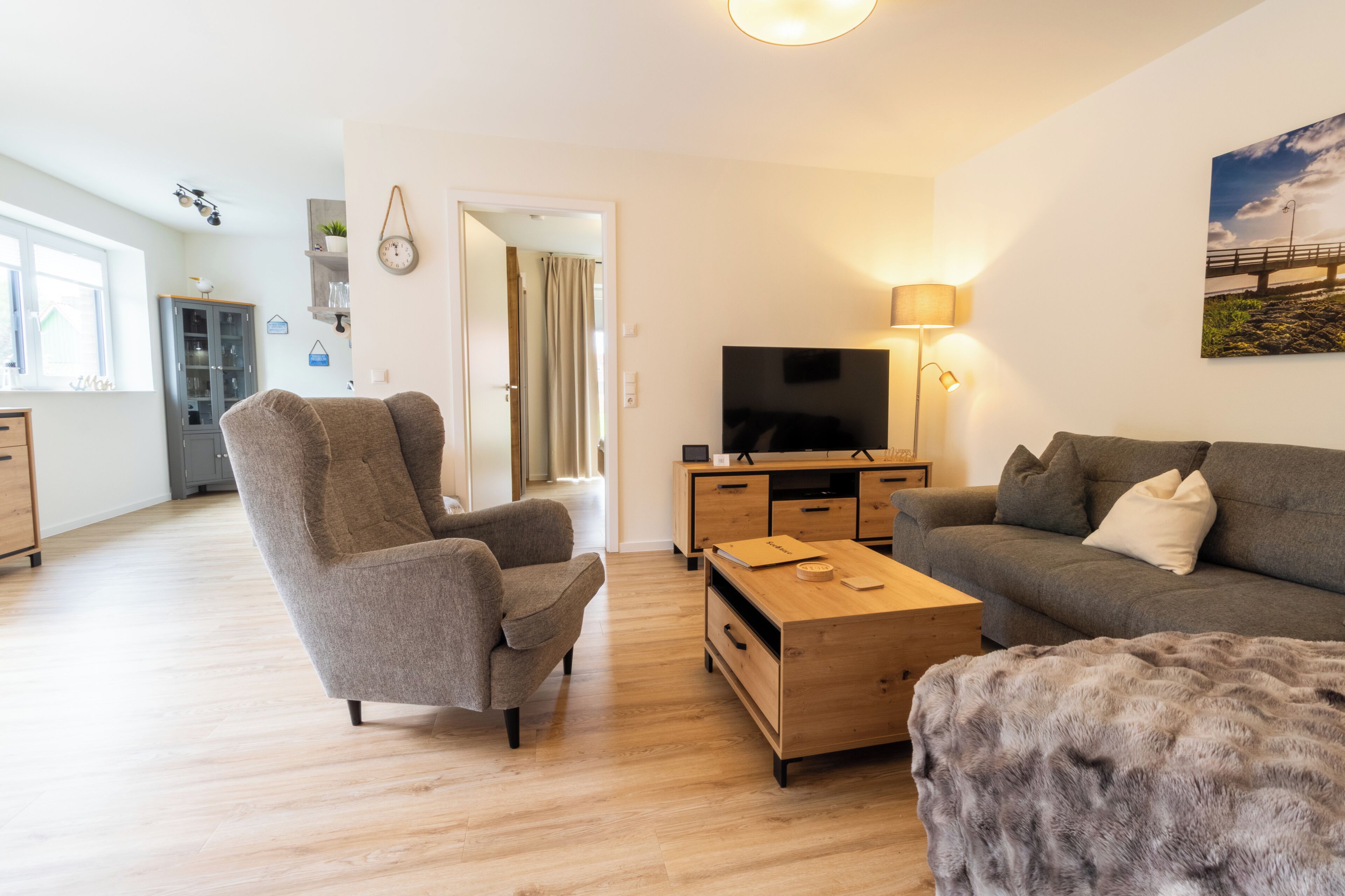A modern living room with a sofa, armchair, coffee table, TV, and lamp.