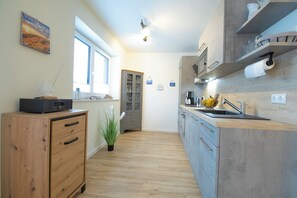 Eine moderne Küche mit Holzschränken, einem eingebauten Ofen und einem großen Fenster.