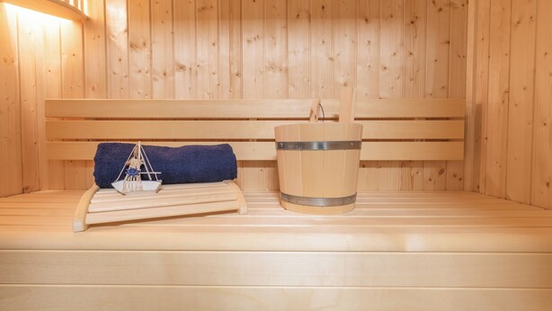 Un sauna en bois avec un banc, une serviette et un seau.