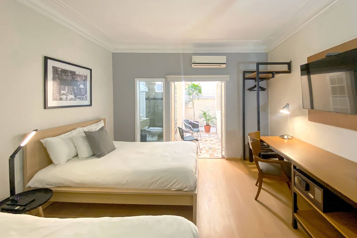 Een slaapkamer met twee bedden, een bureau, een stoel, een lamp en een airconditioning.
