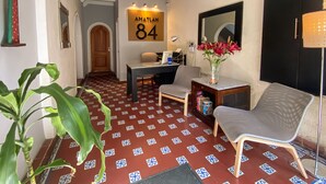 Eine Hotelhalle mit Empfangsschalter, Sitzgelegenheiten und einer großen Zimmernummer 84 an der Wand.