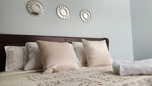 Ein Bett mit floralem Bettbezug, ein dunkles Holz-Kopfteil und drei dekorative Wandspiegel.