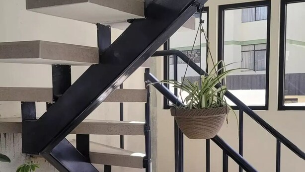 Eine Wendeltreppe mit schwarzen Geländern und Betontritten, die zu einer oberen Etage führt.