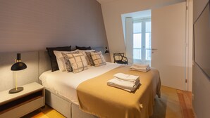Une chambre à coucher avec un lit, une table de chevet, une lampe et une vue sur l’extérieur.
