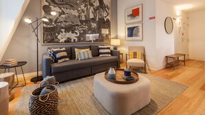 Un salon moderne avec un canapé gris, une table basse et une grande œuvre d’art abstraite accrochée au mur.