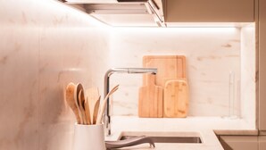 Une cuisine moderne dotée d’un plan de travail en marbre, d’un évier et de planches à découper en bois.