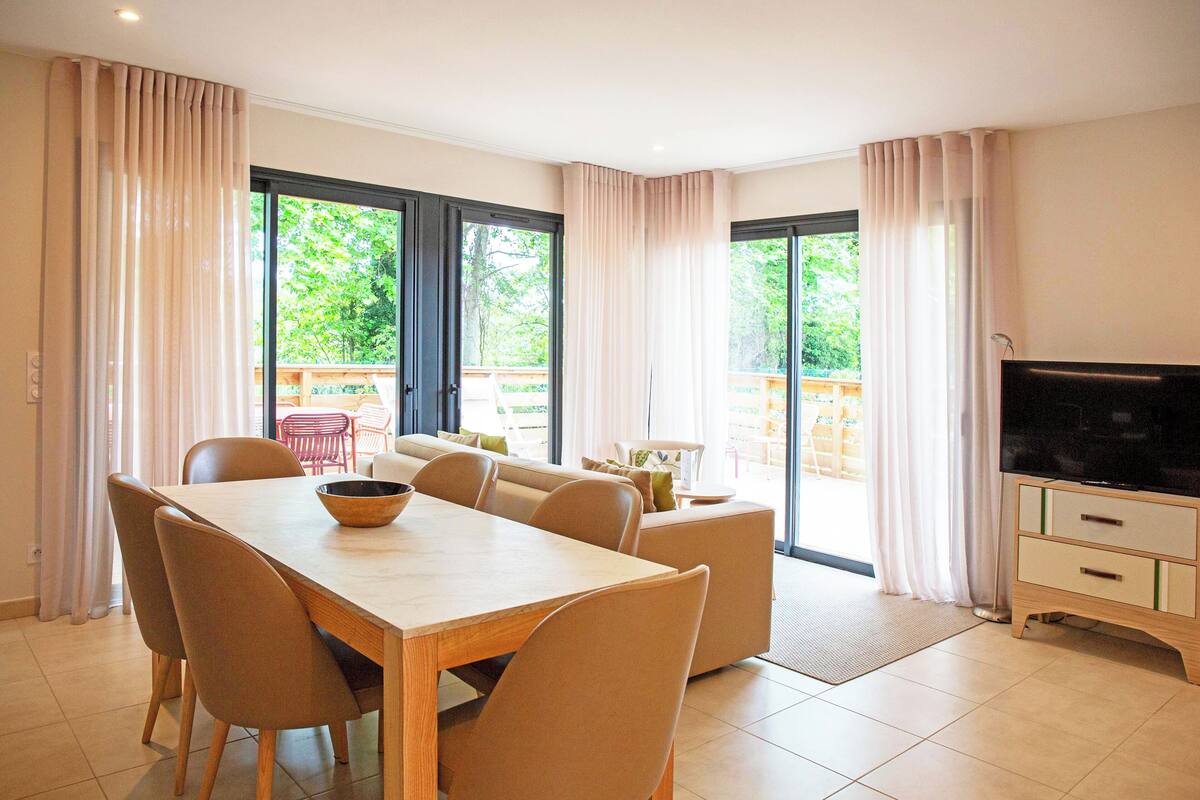 Una sala de estar moderna con una mesa de comedor, sofás y un televisor.