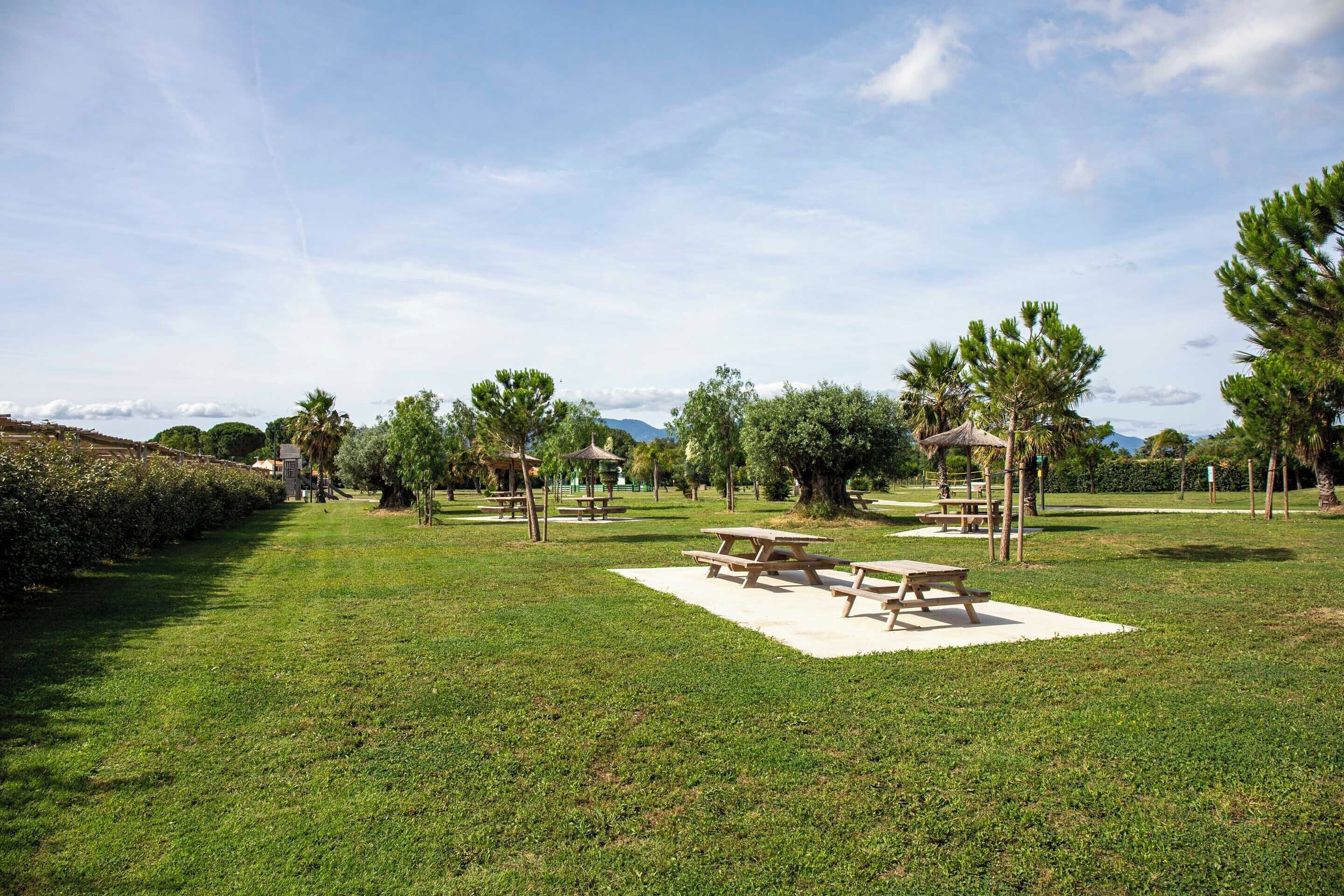 A park with picnic tables, benches, and a gazebo.