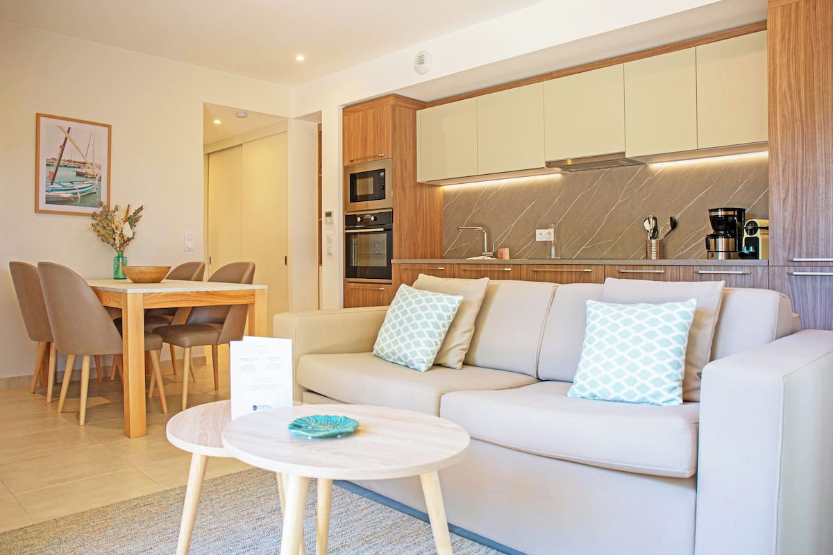 Una sala de estar moderna con sofá, mesa de comedor y área de cocina.