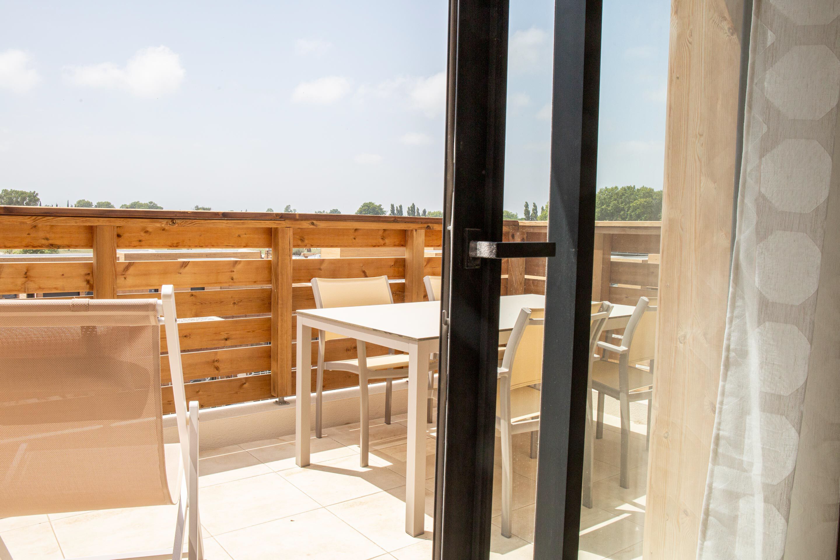 Un patio al aire libre con una terraza de madera, una mesa blanca y sillas.