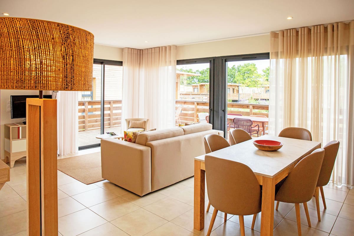 Una sala de estar moderna con un sofá, una mesa de comedor, sillas y un televisor.