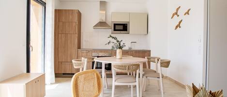 A modern kitchen with wooden cabinets, a round dining table, and wicker chairs.