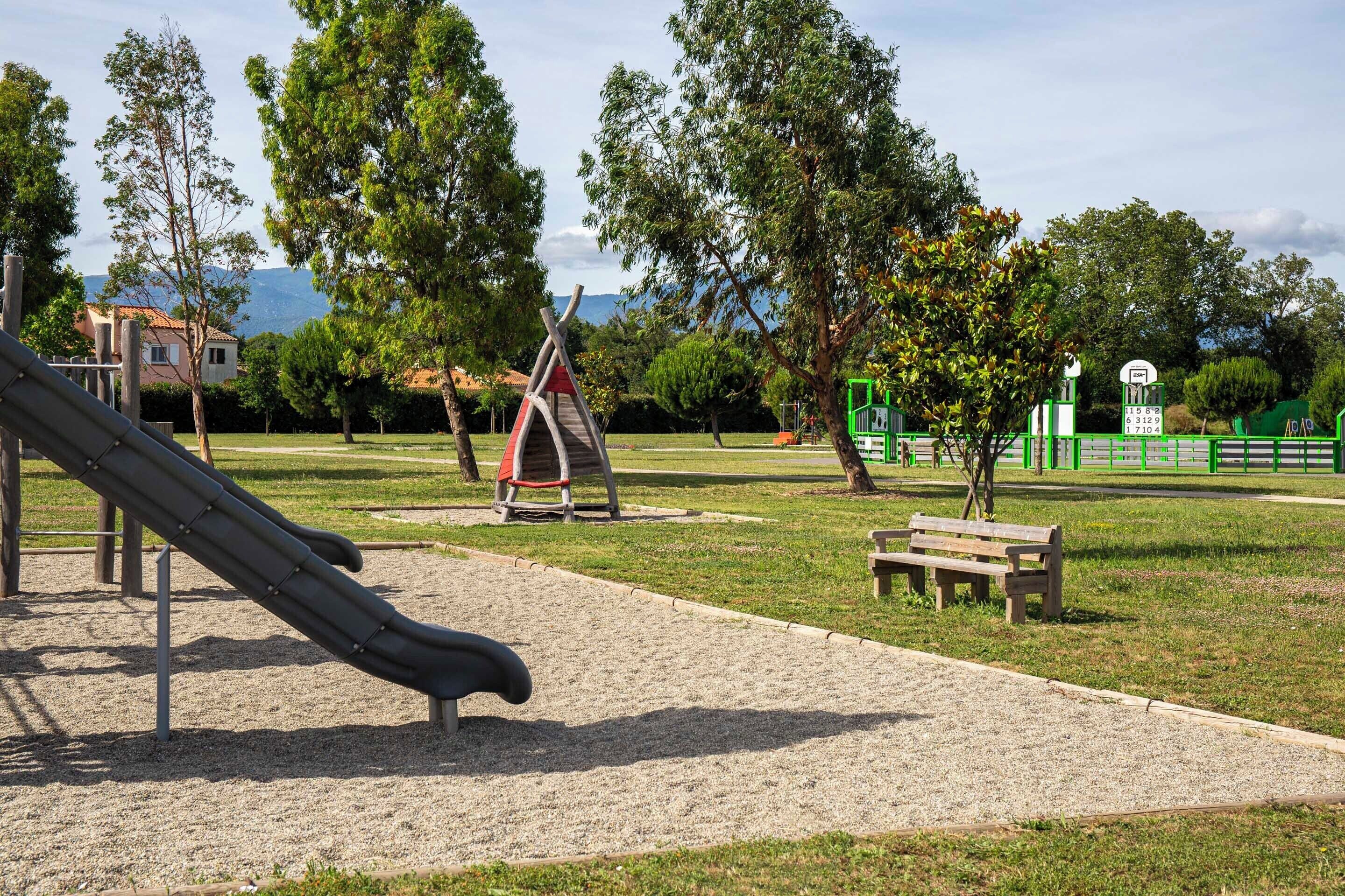 A playground with a slide, swings, and a bench.