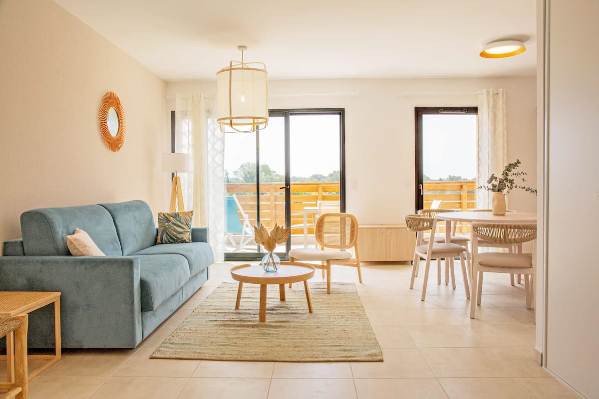Una sala de estar con sofá, una mesa de centro y un comedor con sillas y una mesa.