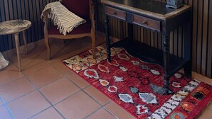A room with a wooden chair, a small table, a desk, a patterned rug, and a mirror on the wall. - Barraconu (Porto-Vecchio)
