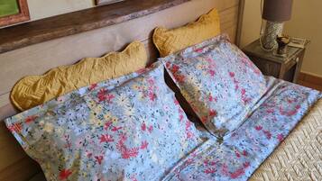 A bed with floral bedding, a wooden headboard, and a bedside table with a lamp.