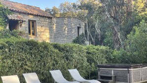 A stone building with a tiled roof, surrounded by dense greenery. - Barraconu (Porto-Vecchio)