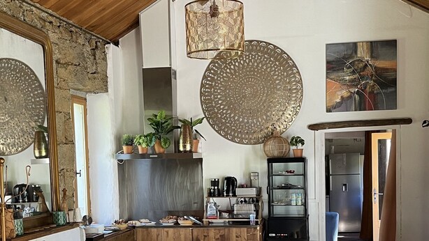 A spacious kitchen with wooden cabinets, a dining area with a table and chairs, and a hanging light fixture. - Barraconu (Porto-Vecchio)