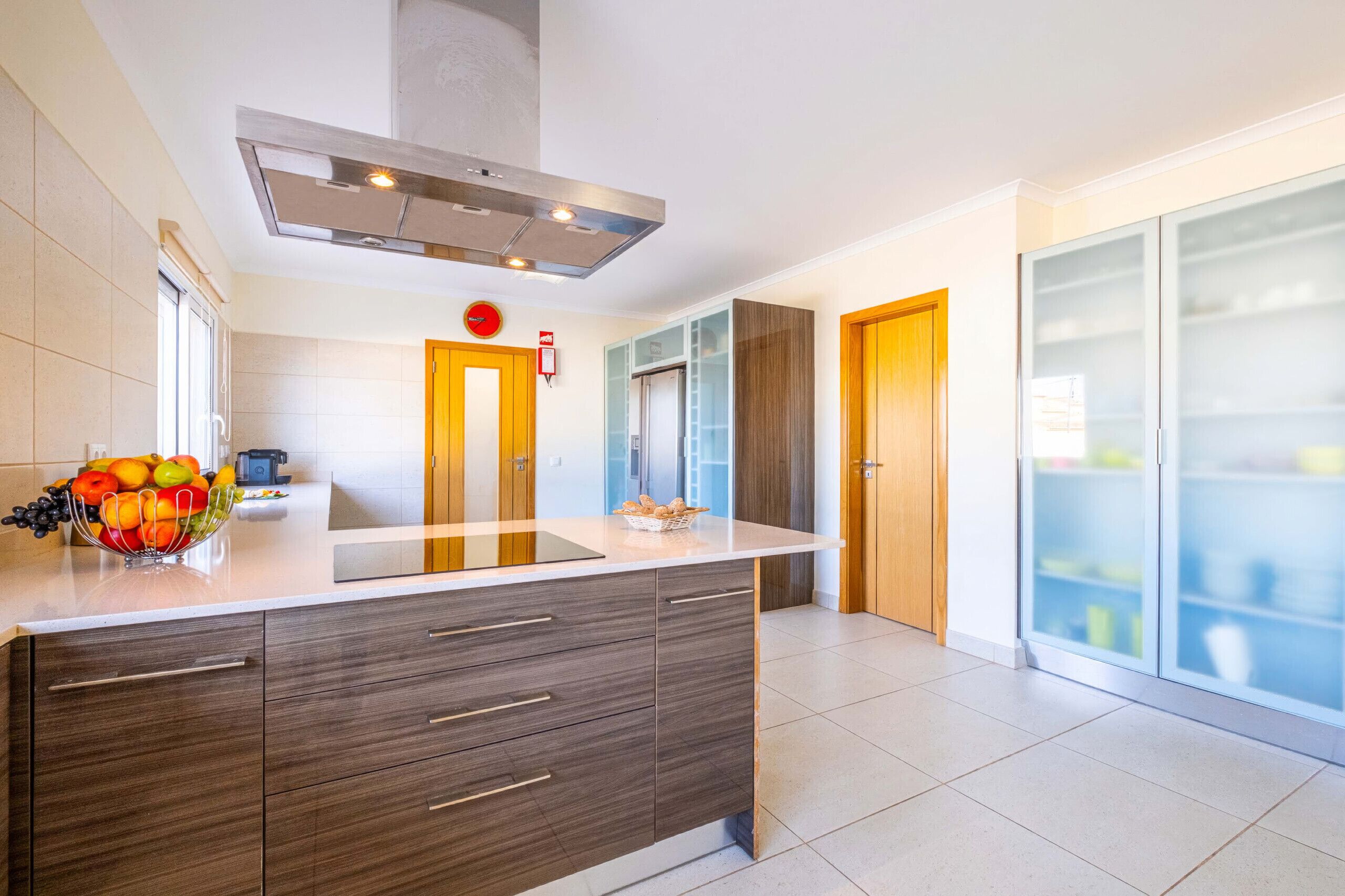 A modern kitchen with a central island, a built-in oven, and a stainless steel range hood.