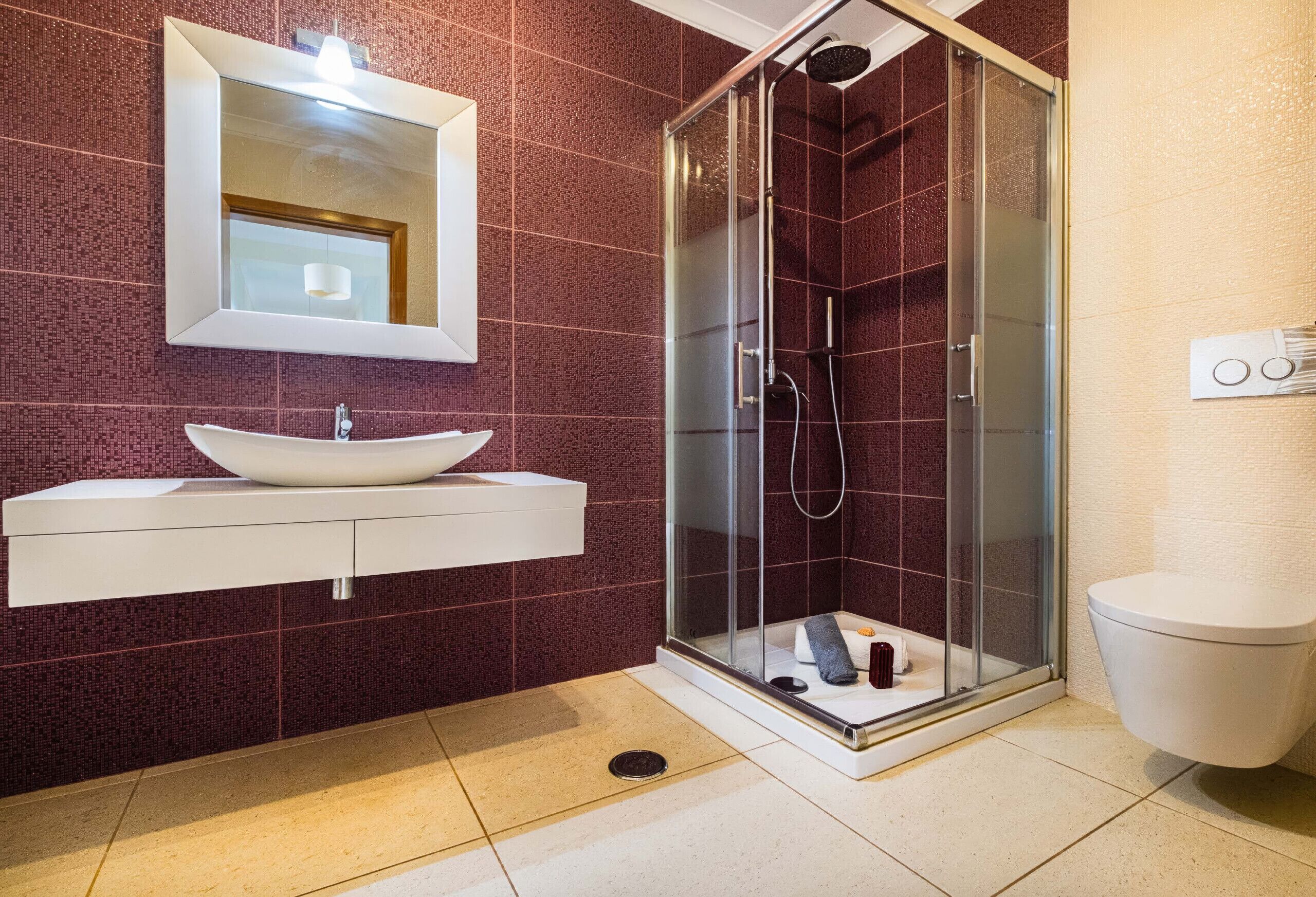 A modern bathroom with a glass-enclosed shower, a white sink, and a mirror above it.