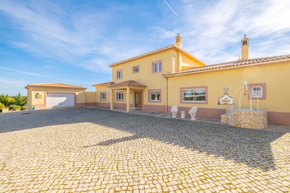 A two-story building with a tiled roof and a paved courtyard. - Villa w/ Heatable Pool and Jacuzzi in Carvoeiro (Carvoeiro)