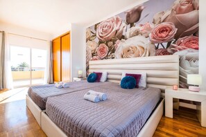 Une chambre d’hôtel avec un grand lit, deux oreillers, une table de chevet et un mur orné d’une fresque florale.