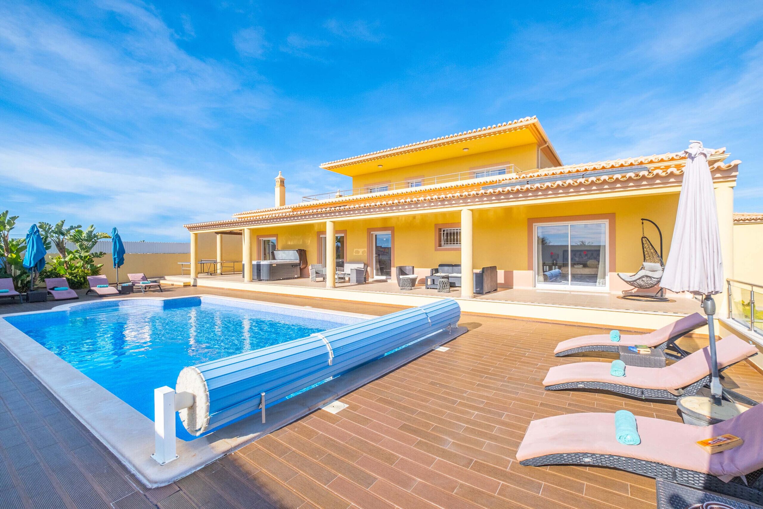 A swimming pool with lounge chairs and a covered patio area.