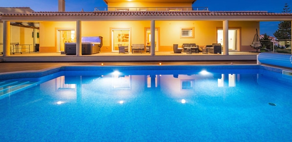 Une piscine avec un patio couvert, du mobilier d’extérieur et un jacuzzi.