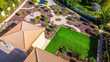 Vista aerea di un giardino curato con un prato centrale, circondato da siepi e alberi di diverse varietà.
