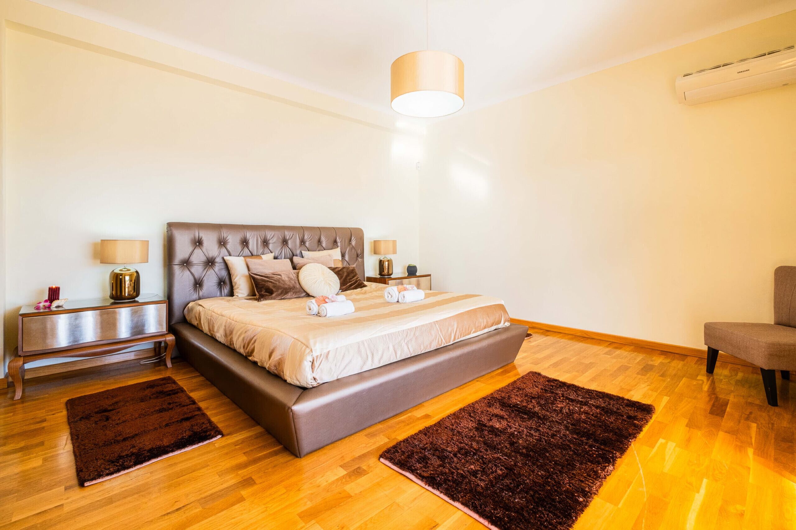 Una camera da letto moderna con un letto grande, comodini, una poltrona e un condizionatore d'aria.